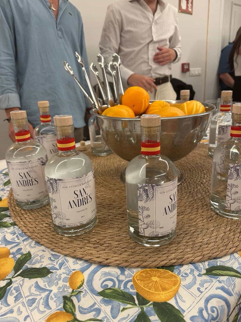 Botellas de San Andrés y un cuenco de naranjas sobre un mantel con naranjas
