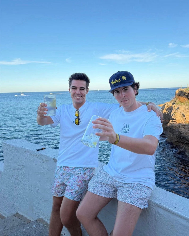 Dos amigos brindando con vasos altos frente al mar