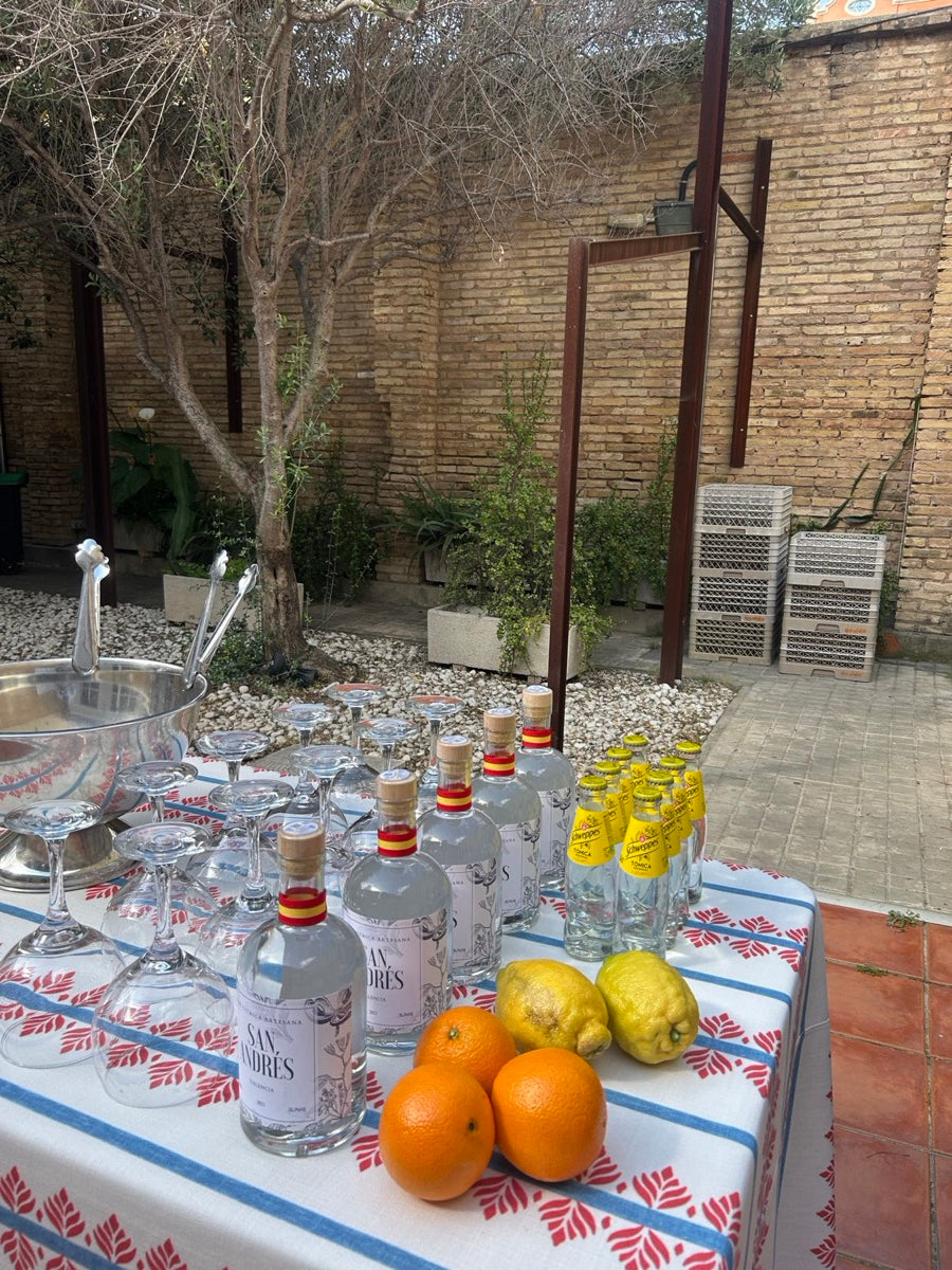 Botellas de San Andrés con naranjas y limones sobre un mantel bordado